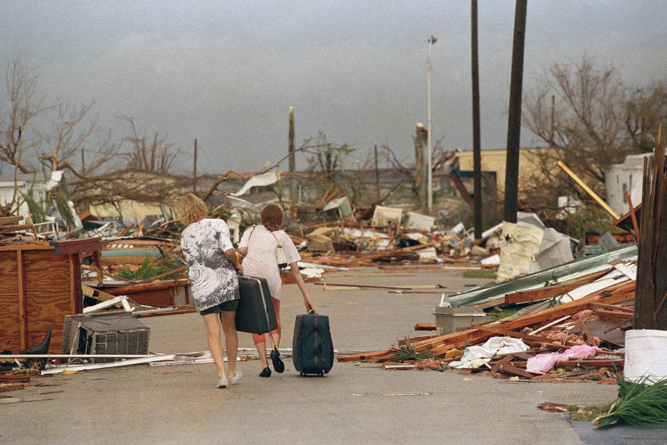 <p>Joan Wallach, left, and her daughter Brenda, right, walk through the debris that was the Royal Palm Trailer Court in Homestead, Fla., Aug. 25, 1992, carrying the only possessions they could salvage from the trailer they lived in before Hurricane Andrew hit the South Florida city. (AP Photo/Lynne Sladky) </p>