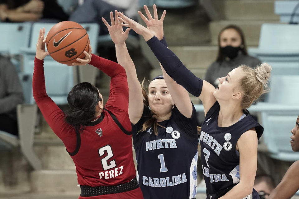 North Carolina State guard Raina Perez (2) shoots while North Carolina guard Alyssa Ustby (1) and guard Petra Holesinska (2) defend during the second half of an NCAA college basketball game in Chapel Hill, N.C., Sunday, Feb. 7, 2021. (AP Photo/Gerry Broome)