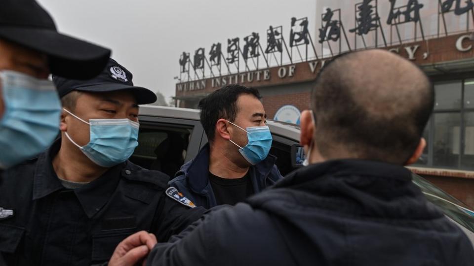 護衛員在中國科學院武漢病毒研究所外阻擋記者靠近世衛組織專家車隊（3/2/2021）