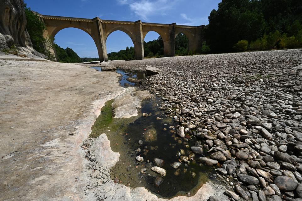 A photograph shows the parched river bed of the Gardon near the Saint-Nicolas de Campagnac bridge in Saint-Anastasie, southern France, after a heat wave hit France, on June 20, 2022. - The heat wave is gradually ending on June 20, 2022 in France, and a new wave of thunderstorms will arrive in the evening on the Atlantic coast and the Centre-Val-de-Loire, predicted Meteo France, which has placed 21 departments under orange storm watch. (Photo by Pascal GUYOT / AFP) (Photo by PASCAL GUYOT/AFP via Getty Images)