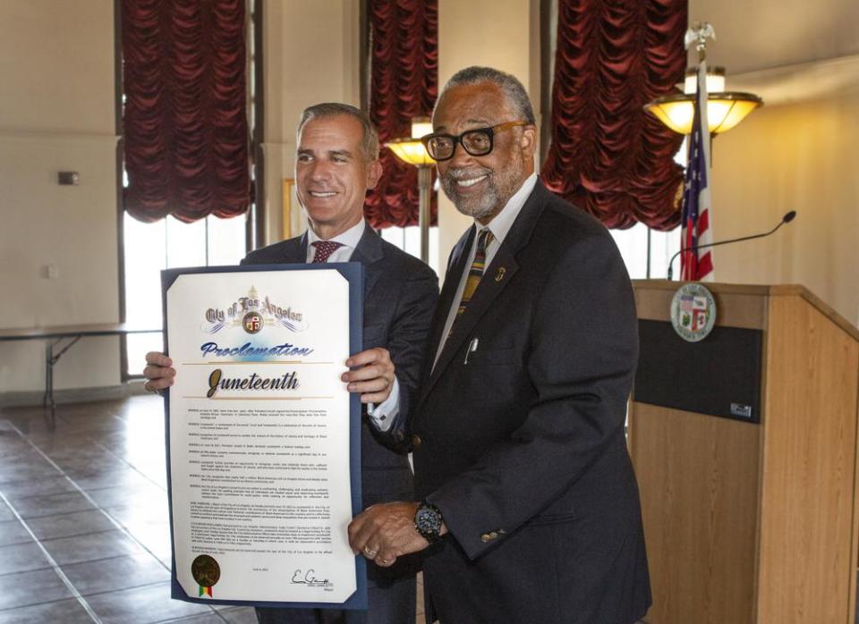 In this photo provided by the Office of Los Angeles Mayor Eric Garcetti, Garcetti, left, is joined by Councilmember Curren Price after signing a proclamation making Juneteenth an official City holiday on Monday, June 6, 2022, at LA City Hall in Los Angeles. (Office of Los Angeles Mayor Eric Garcetti via AP)