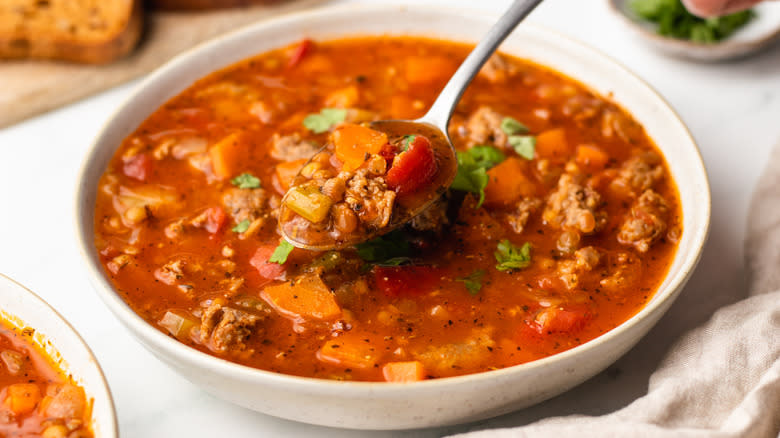 spooning from bowl of sausage lentil soup