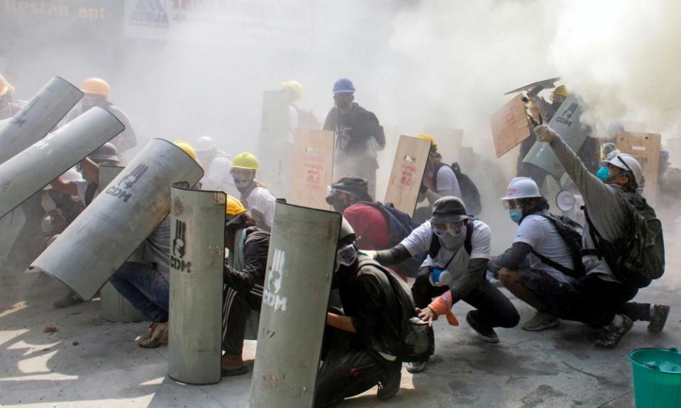 Protesters take cover as they clash with riot police in Yangon