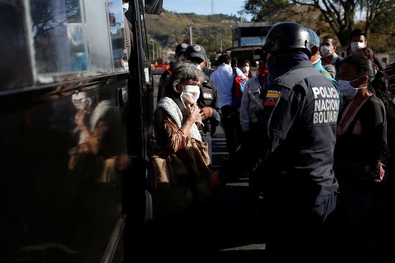 People wearing protective masks are asked by officers of the Bolivarian National Police to leave a bus at a checkpoint after the start of quarantine in response to the spreading of coronavirus disease (COVID-19) in Caracas