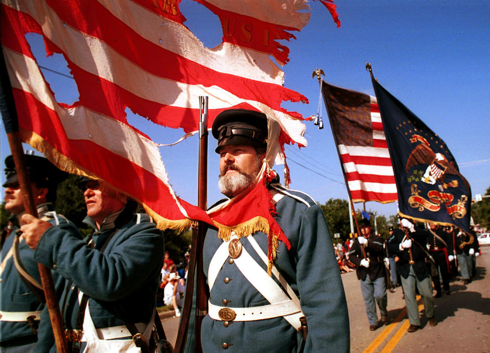 <p>Kevin Doughtie, right, leads the 1st United States Infantry Regiment reenactment group as they march with a battle-worn 19th century flag, July 4, 2000 during the Fourth of July Parade in Arlington, Texas. (Photo: Tom Fox/Arlington Morning News/Getty Images) </p>