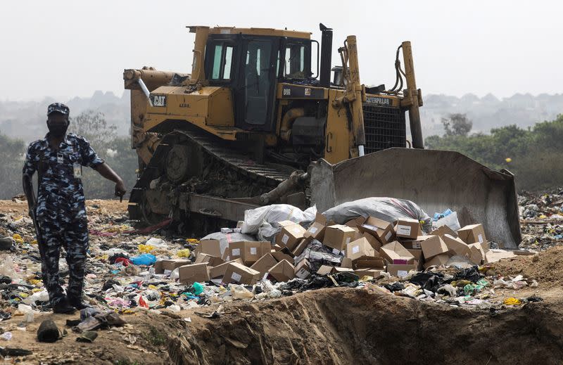 Police officer stands next to boxes of expired AstraZeneca COVID-19 vaccines at Gosa dump site in Abuja