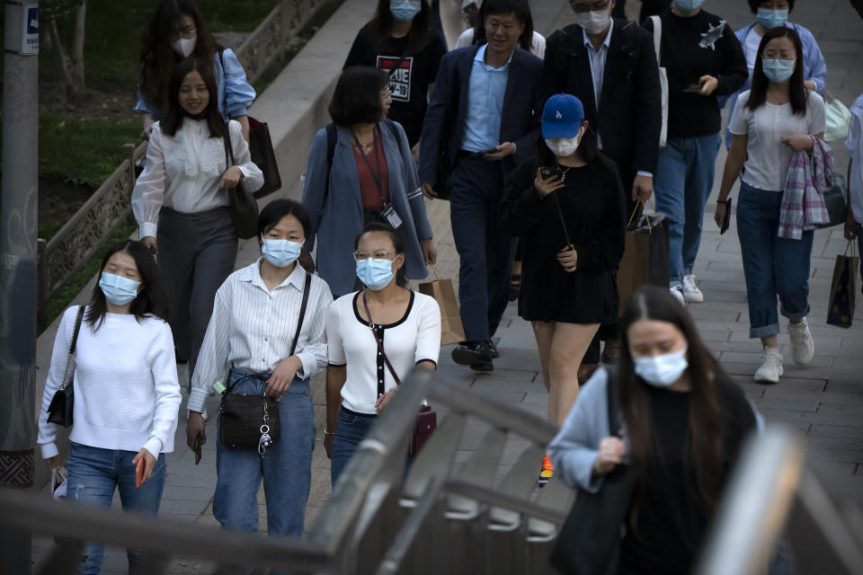People wearing face masks to protect against COVID-19 walk along a street in the central business district in Beijing, Thursday, Sept. 16, 2021. China on Thursday reported several dozen additional locally-transmitted cases of coronavirus as it works to contain an outbreak in the eastern province of Fujian. (AP Photo/Mark Schiefelbein)