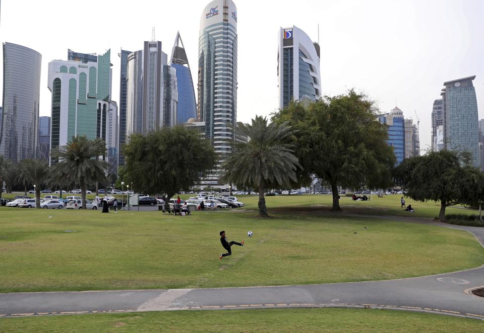 FILE - A boy plays with a soccer ball at Dafna Park in Doha, Qatar, Saturday, May 4, 2019. World Cup fans could bring political tensions to quiet Qatar. (AP Photo/Kamran Jebreili, File)