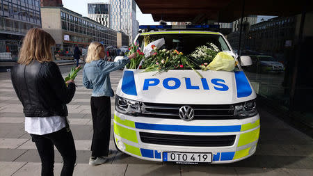 A woman puts flowers on a police vehicle near the Ahlens department store following Friday's attack in central Stockholm, Sweden, April 9, 2017. REUTERS/Philip O'Connor