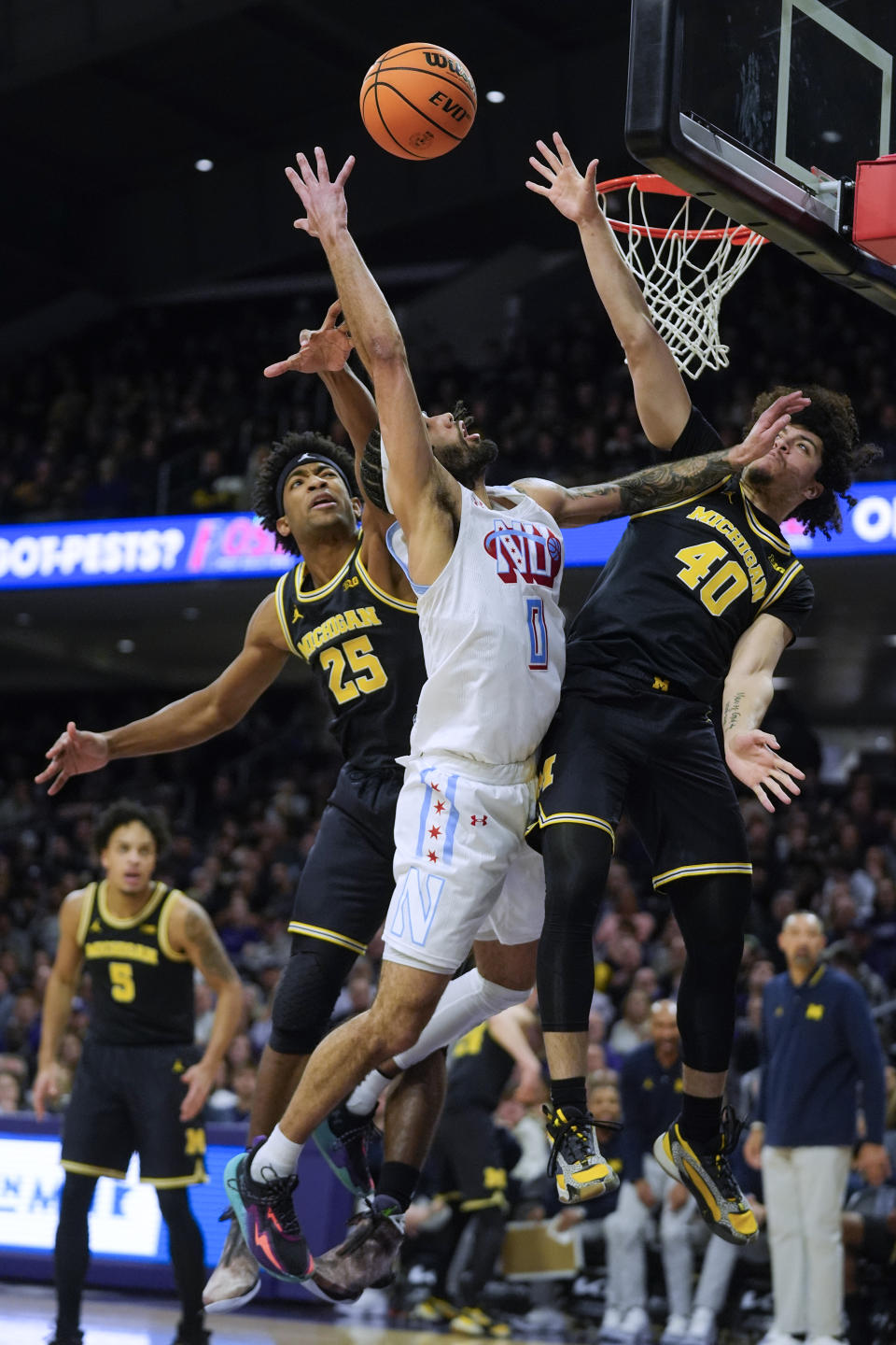 Northwestern guard Boo Buie (0) is stopped by Michigan guard Jace Howard (25) and guard George Washington III (40) during the first half of an NCAA college basketball game Thursday, Feb. 22, 2024, in Evanston, Ill. (AP Photo/Erin Hooley)