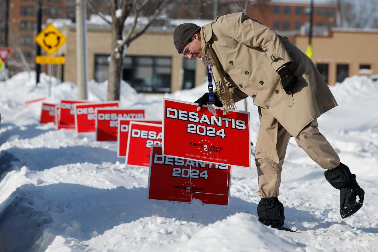 A volunteer plunges campaign signs for Florida Gov. Ron DeSantis into deep snow outside the Chrome Horse Saloon one day before the Iowa Caucuses on Jan. 14, 2024, in Cedar Rapids, Iowa.