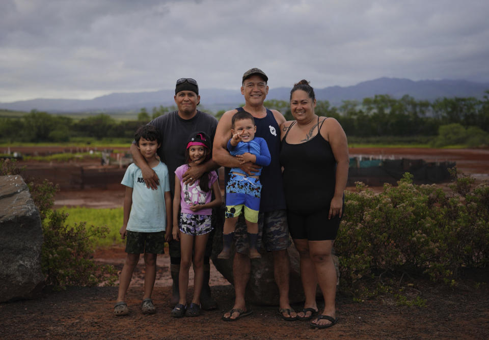 Kurt Kuali'i, father of Elijah Kuali'i and Arianna Kuali'i, stands with his fellow salt makers, Ivan Kaneko, Tanya Kaneko and their son Taivan Kaneko, for a portrait in front of the Hanapepe salt patch on Thursday, July 13, 2023, in Hanapepe, Hawaii. (AP Photo/Jessie Wardarski)