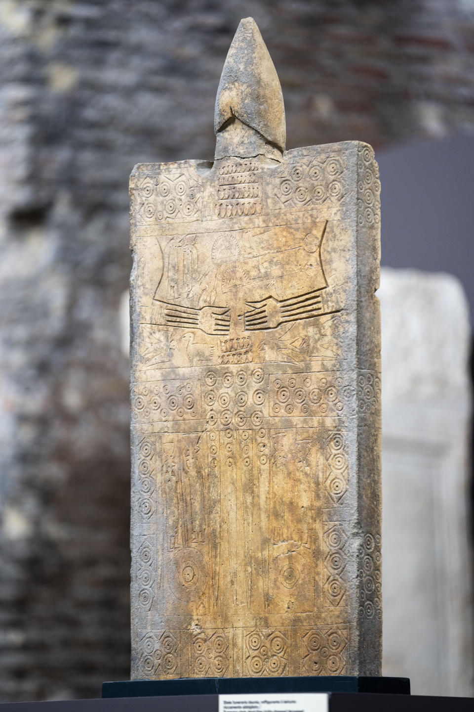 A 7th-6th century BC funerary stele found in southern Italy near Foggia, and depicting a richly-dressed deceased, is on display at the exhibition 'Between us and the ancients. The instant and eternity' in Rome's Diocletian Baths, Wednesday, May 3, 2023. The exhibition will open to the public from May 4 through July 30, 2023. (AP Photo/Domenico Stinellis)