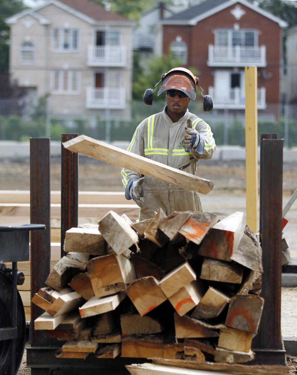 In this Wednesday, Aug. 15, 2012 photo, Andre Scott, of Jersey City, N.J., throws a piece of trimmed wood cut from discarded tree trunk at Citilog in Newark, N.J. The Newark company takes unwanted trees from the so-called urban forest — parks, yards, streets and wherever else a tree might grow in a city — and turns them into furniture, flooring and other materials. (AP Photo/Mel Evans)