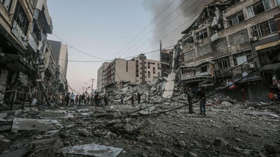 Menschen stehen vor dem eingestürzten Al-Shorouk Tower, nachdem dieser bei einem israelischen Luftangriff getroffen wurde.