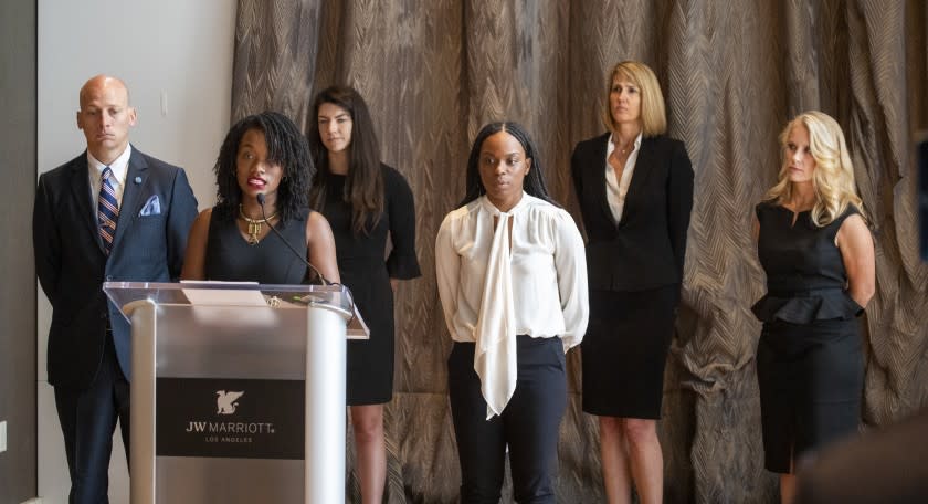 LOS ANGELES, CA - JUNE 18: Janesha Morgan, fourth from left, listens as Shernae Hughes, second from left, both Black survivors of alleged sexual assault by former USC gynecologist George Tyndall, speaks while they and their attorneys hold a news conference to call on USC Board of Trustees Chairman Rick Caruso to "keep his promise to release an internal investigation of the Tyndall scandal," which they allege also included decades of racism. Attorney Vince Finaldi, left, of Manly, Stewart & Finaldi Lawyers, says Caruso has backtracked on his promise to release the Tyndall investigation report, stating the need to "balance" transparency against privacy and `the concerns of outside investigations and litigation." Photos taken at The Mixing Room at JW Marriott, L.A. LIVE Thursday, June 18, 2020 in Los Angeles, CA. (Allen J. Schaben / Los Angeles Times)