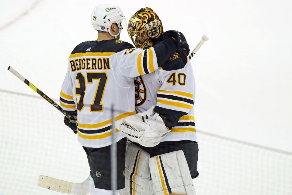 Boston Bruins center Patrice Bergeron (37) embraces teammate Tuukka Rask (40) after an NHL hockey game, Monday, May 3, 2021, in Newark, N.J.  (AP Photo/Kathy Willens)