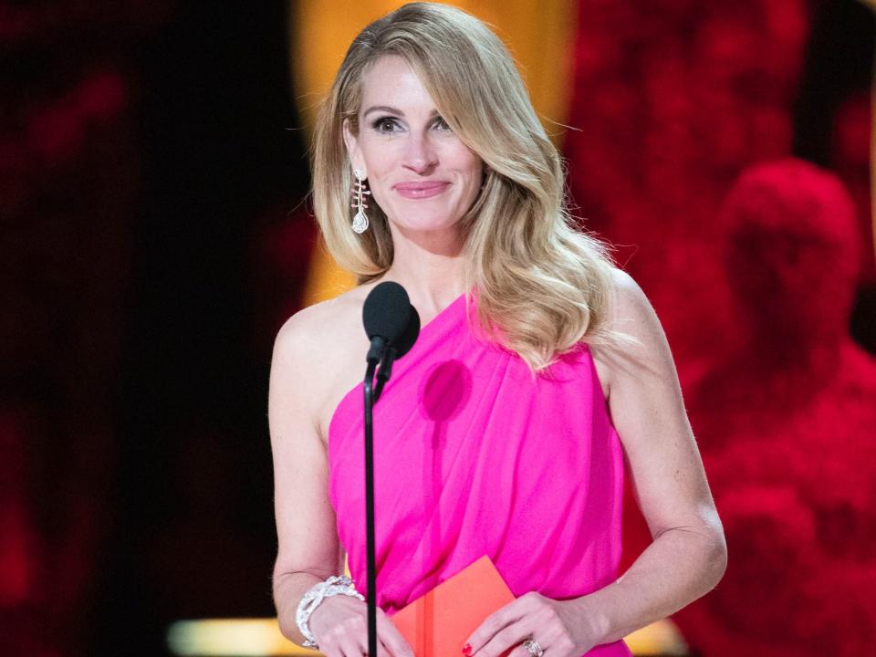 Julia Roberts, in a hot-pink, one shoulder gown, stands onstage at the 91st Academy Awards with an envelope in her hand.