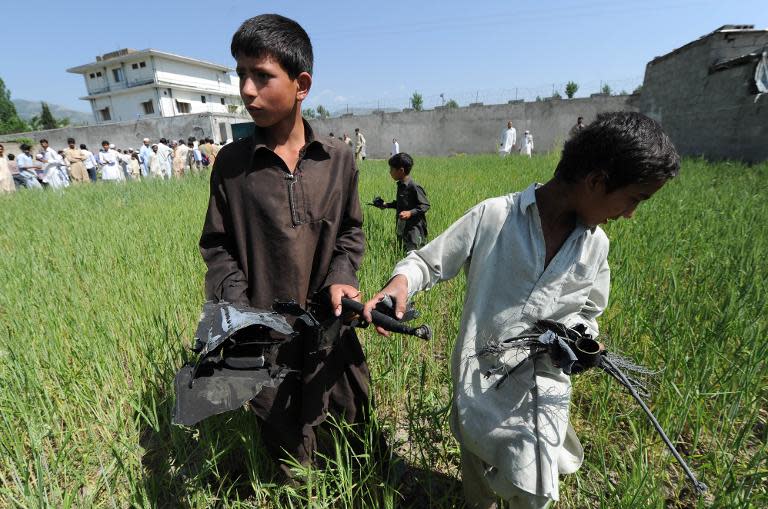 Pakistani children collect debris at the site of the crashed helicopter outside the hideout house of Al-Qaeda leader Osama bin Laden on May 3, 2011