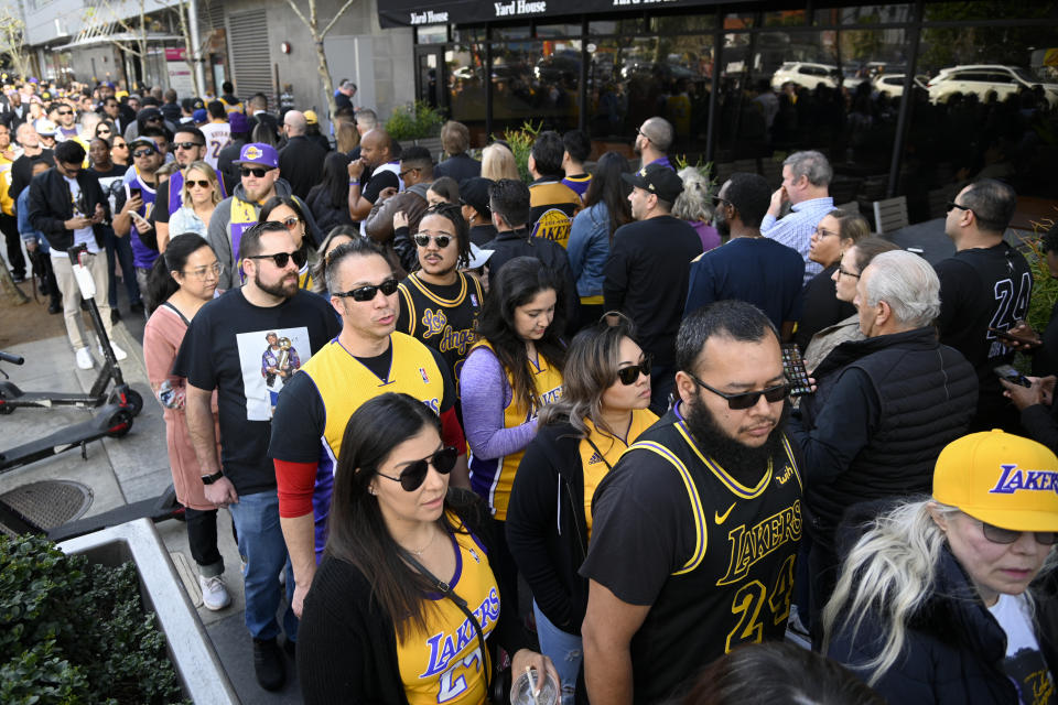 Aficionados hacen fila cerca del Staples Center antes de un homenaje a la fallecida estrella de los Lakers de Los Ángeles Kobe Bryant y su hija Gianna, el lunes 24 de febrero de 2020, en Los Ángeles. (AP Foto/Kelvin Kuo)