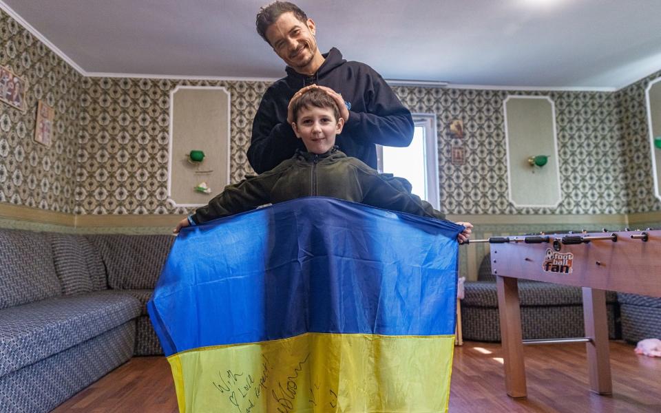 UNICEF Goodwill Ambassador Orlando Bloom poses with Yehor, 8, holding a Ukrainian flag signed by Orlando, in Demydiv, Ukraine - UNICEF/UN0820049/Skyba/Newsflash/UNICEF/UN0820049/Skyba/Newsflash