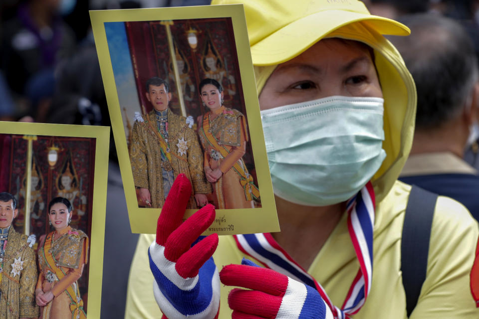 A supporter of the Thai monarchy displays images of King Maha Vajiralongkorn and Queen Suthida during a gathering outside German Embassy in central Bangkok, Thailand Monday, Oct. 26, 2020. The royalists gathered to defend pro-democracy protesters' contention that King Maha Vajiralongkorn spends much of his time in Germany conducting Thai political activities. German government officials have recently expressed concern over political activities the king might be conducting on the Germany's soil. (AP Photo/Gemunu Amarasinghe)