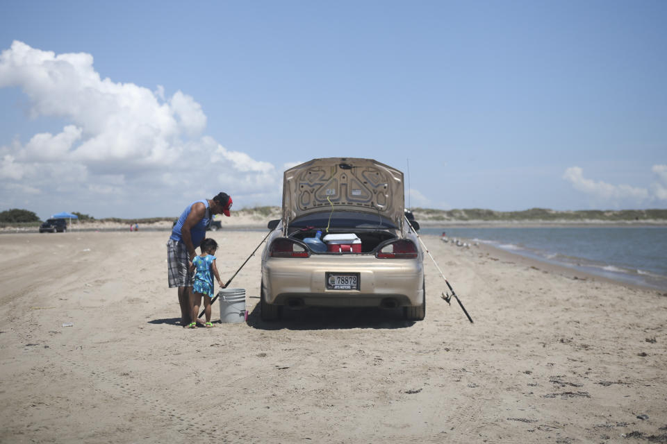 In this Aug. 3, 2019 photo, a child watches a grown up clean a fish during a fishing trip to Playa Bagdad near the border city of Matamoros, Mexico. Playa Bagdad appeared on maps in 1848, when the border was drawn during the Mexico-American War. (AP Photo/Emilio Espejel)