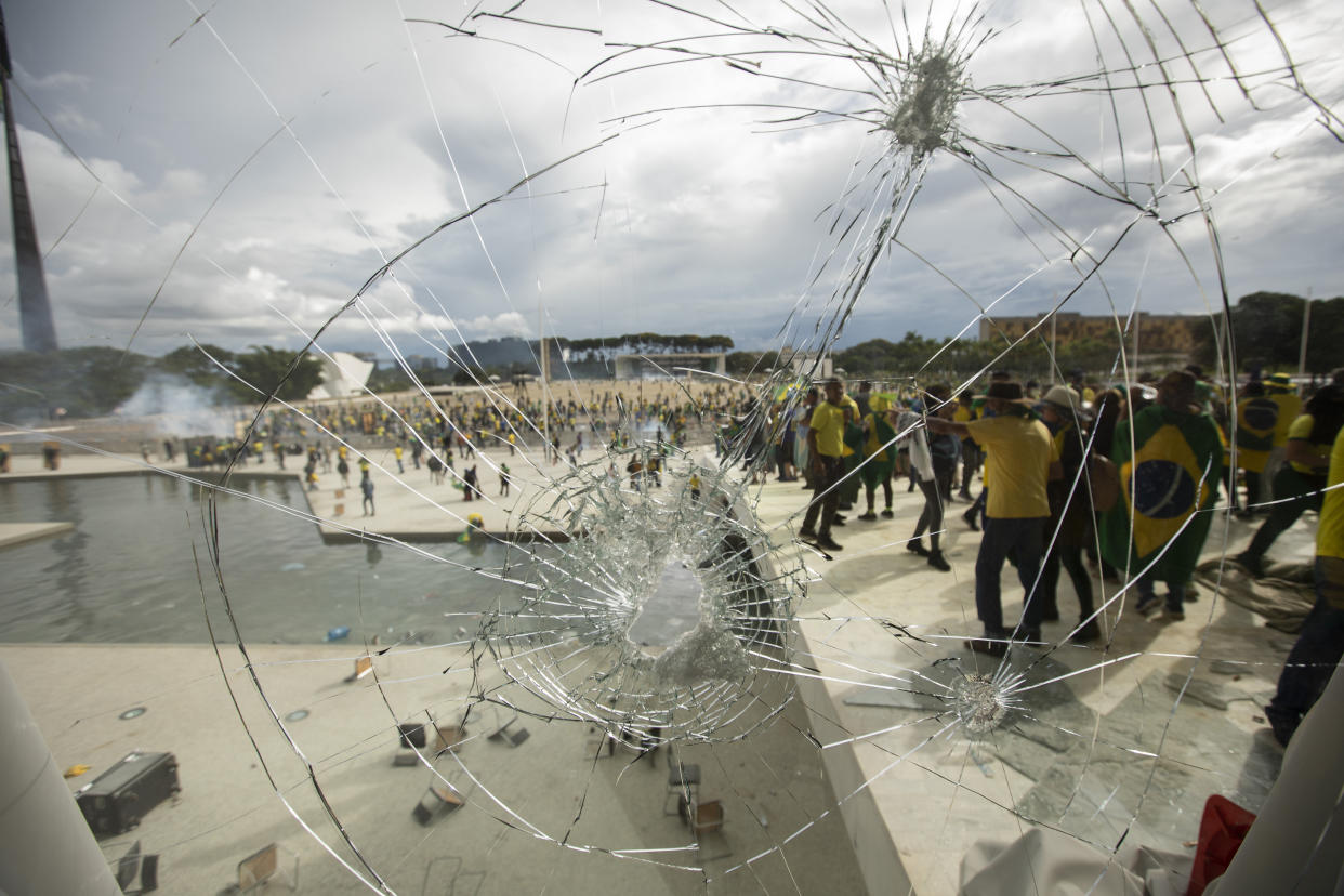 In a view through a broken window, supporters of former President Jair Bolsonaro clash with security forces as they break into Planalto Palace and raid Supreme Court in Brasilia, Brazil, January 8, 2023. (Joedson Alves/Anadolu Agency via Getty Image