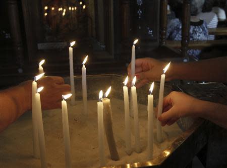 Syrian women light candles before attending mass in the Catholic Patriarchate in Damascus, September 7, 2013. REUTERS/Khaled al Hariri