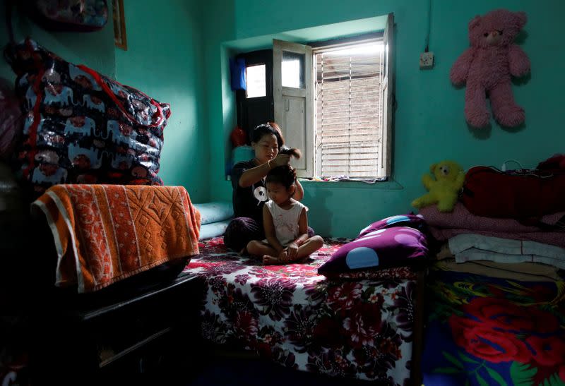 Nepali housewife Shiba Kala Limbu ties up her five-year-old daughter Masim Limbu's hair in Kathmandu