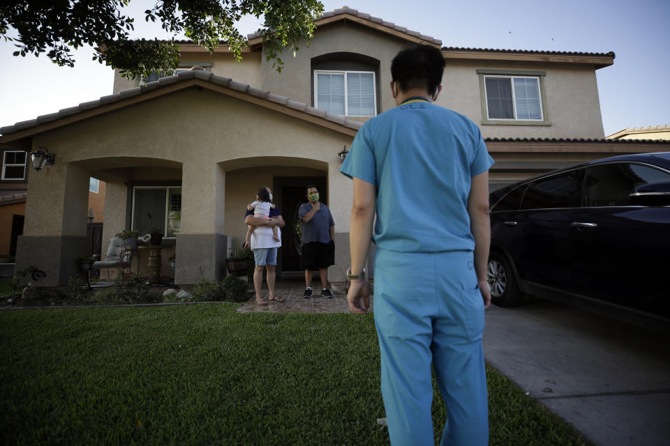 Dr. Tien Vo speaks to a family quarantining after testing positive for the coronavirus Thursday, July 23, 2020, in Calexico, Calif. Vo and members of his clinic bring food to patients that test positive and agree to quarantine. (AP Photo/Gregory Bull)