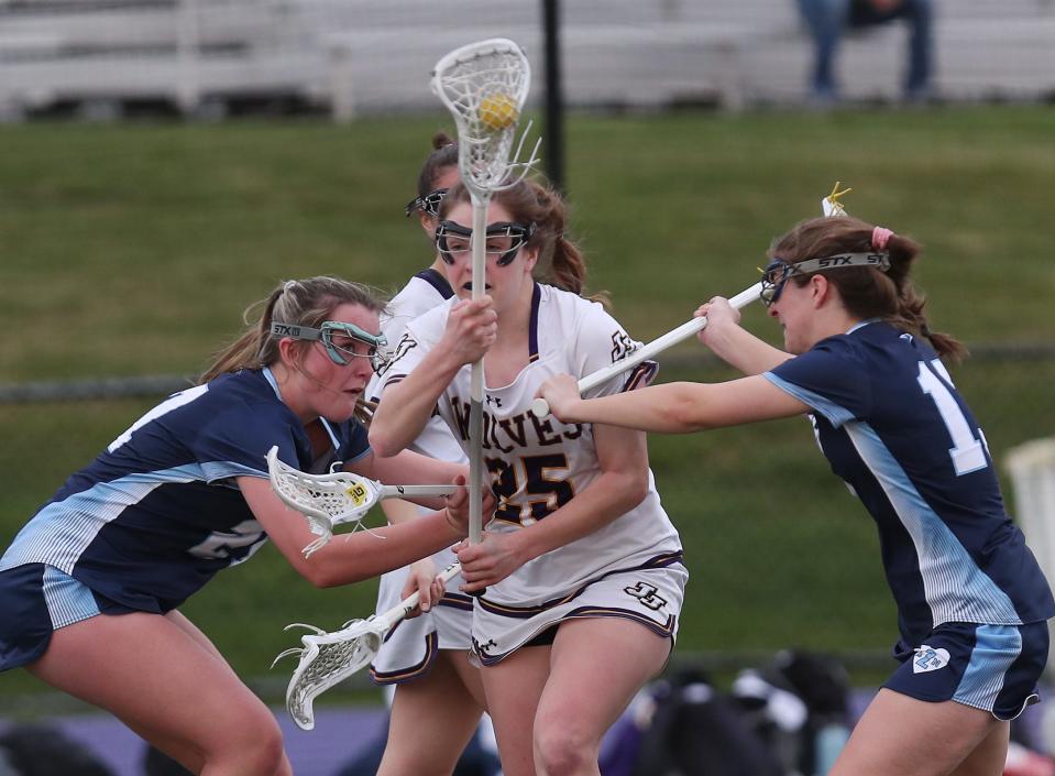 John Jay's Annie Brennan (25) gets between Suffern's Nevin Sullivan (27) and Caitlin Ruggerio (13) as she drives to the goal during girls lacrosse action at John Jay High School in Cross River High  April 11, 2023. John Jay won the game 17-9.