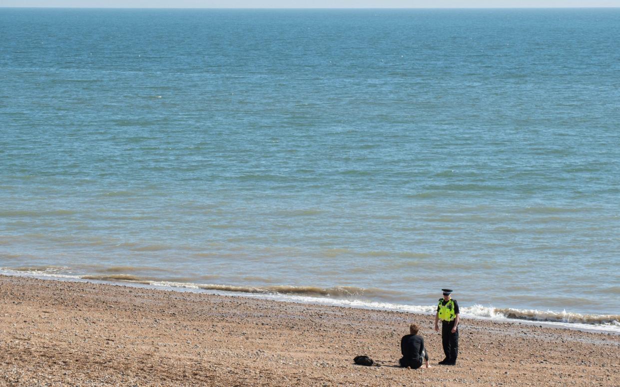 Narrowed horizons: a police officer questions a beachgoer in Brighton, April 2020 - Alamy