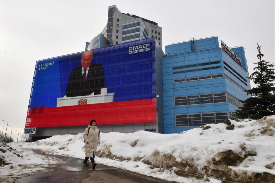 A woman walks past a screen displaying a broadcasting of Putin's annual state of the nation address on the facade of a building in Moscow (AFP via Getty Images)