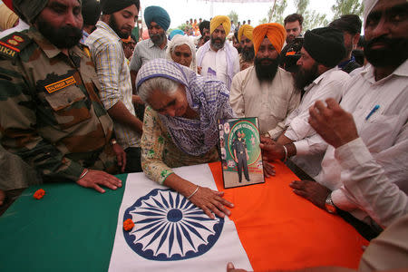 A relative touches the coffin of Paramjit Singh, an Indian army soldier who the Indian army says was killed by Pakistani soldiers while patrolling the de facto border in the disputed Kashmir region on Monday, in the village of Vein Poin on the outskirts of Amritsar, India May 2, 2017. REUTERS/Munish Sharma