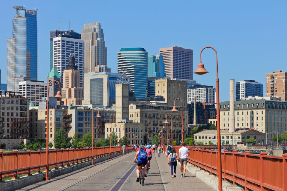 bridge in minneapolis with cyclists and skyline in the background