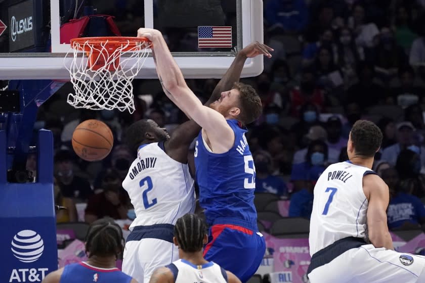 Dallas Mavericks' Eugene Omoruyi (2) and Dwight Powell (7) defend as Los Angeles Clippers center Isaiah Hartenstein (55) dunks during the second half of a preseason NBA basketball game in Dallas, Friday, Oct. 8, 2021. (AP Photo/Tony Gutierrez)