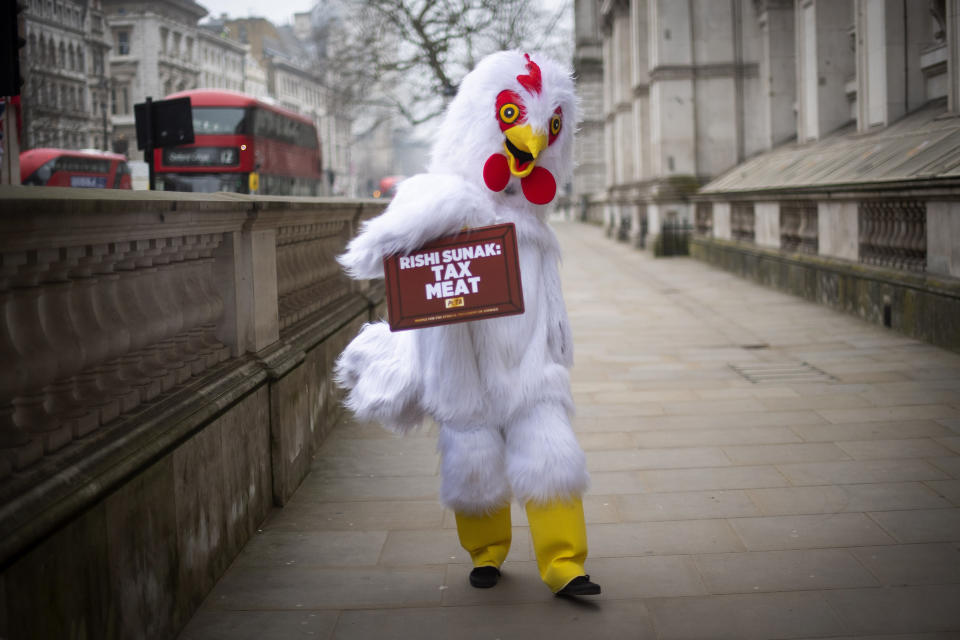 An animal rights activist dressed as a chicken with sign calling on Chancellor of the Exchequer Rishi Sunak to tax meat, outside Downing Street in London Wednesday March 3, 2021. Sunak is expected to announce tax and spending projections to help workers and businesses hit by the coronavirus pandemic when he delivers his budget to Parliament later Wednesday. (Victoria Jones/PA via AP)