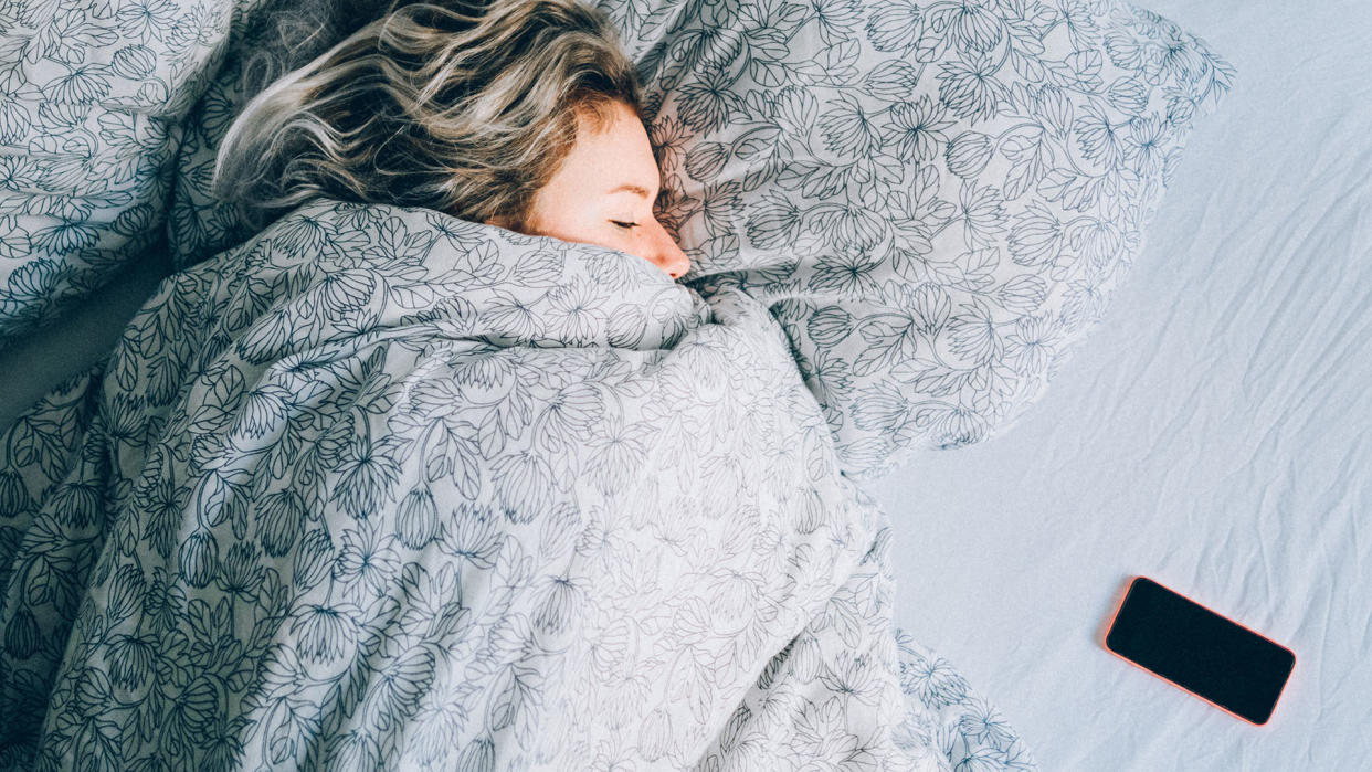  Woman asleep with phone on bed next to her. 