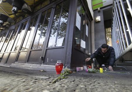 A man places a candle outside one of the attack sites in Paris, November 15, 2015. REUTERS/Jacky Naegelen