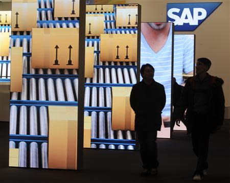 People are pictured beside screens at the booth of German company SAP during preparations at the CeBit computer fair in Hanover in this March, 4, 2012 file picture. REUTERS/Fabian Bimmer