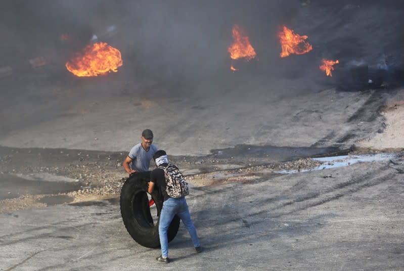 Demonstrators push a tire to be set on fire during a protest targeting the government over an economic crisis, in Nabatiyeh