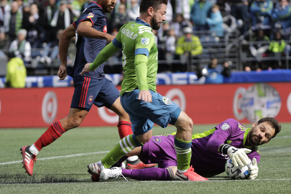 Chicago Fire goalkeeper Kenneth Kronholm, right, grabs the ball as Seattle Sounders midfielder Joao Paulo, center, closes in, during the first half of an MLS soccer match, Sunday, March 1, 2020, in Seattle. (AP Photo/Ted S. Warren)