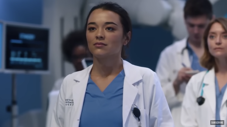 Midori Francis on the set of Grey's Anatomy wearing scrubs and a lab coat