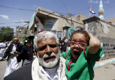 An injured girl reacts as she is carried by a man out of a mosque which was attacked by a suicide bomber in Sanaa March 20, 2015. REUTERS/Khaled Abdullah