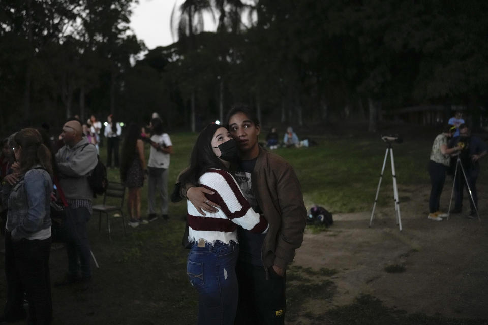 A couple look at the moon during the first blood moon of the year, in Caracas, Venezuela, Sunday, May 15, 2022. (AP Photo/Matias Delacroix)