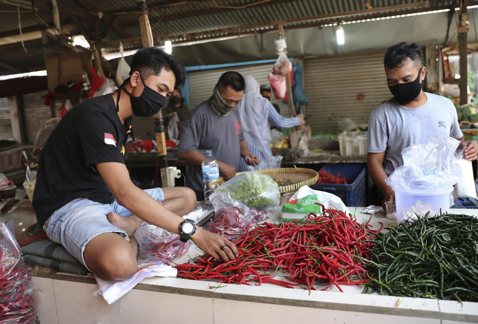 Vendors wearing protective mask as a precaution against the new coronavirus outbreak sort chili peppers at a market in Jakarta, Indonesia, Thursday, June 25, 2020. (AP Photo/Tatan Syuflana)