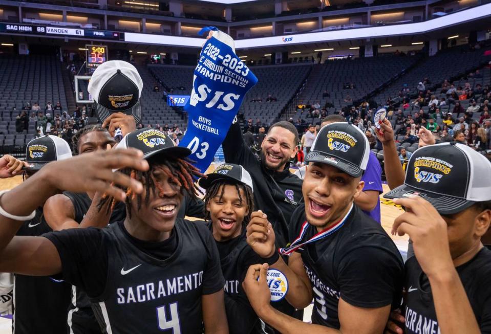 Sacramento Dragons head coach Matt Johnson, center, holds up the Sac-Joaquin Section Division III high school boys basketball championship banner after his team defeated the Vanden Vikings in February.