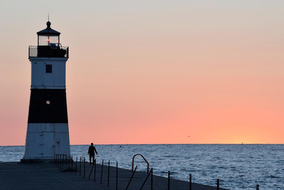 A fisherman works his line just before sunrise near the North Pier Light in the file photo.