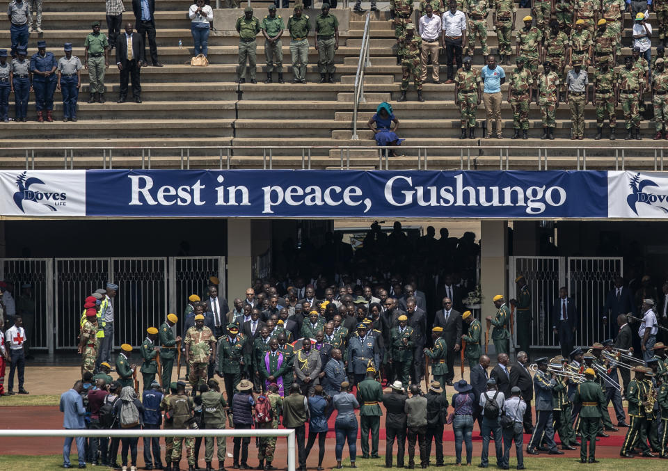 The casket of former president Robert Mugabe, covered by the national flag and followed by family and dignitaries, arrives for a state funeral, under a banner referring to his totem name "Gushungo", at the National Sports Stadium in the capital Harare, Zimbabwe Saturday, Sept. 14, 2019. African heads of state and envoys are gathering to attend a state funeral for Mugabe, whose burial has been delayed for at least a month until a special mausoleum can be built for his remains. (AP Photo/Ben Curtis)